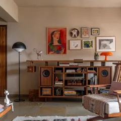 The living room was planned around our clients' vibrant collection of art and furniture. The custom-built media unit, crafted from teak, provides dedicated spaces for their speakers, books, and cherished artifacts.