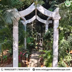 The completed natural stone archway, creating a beautiful and grand entrance to a garden path, surrounded by lush tropical foliage.