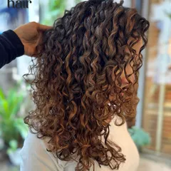 A side profile showing how the balayage highlights weave through the curls, creating depth and movement. This is a great option for a natural, sun kissed effect.