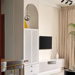 An arched niche elegantly frames a puja cabinet with perforated shutters, integrating a sacred space into the living room's design. The clean lines of the TV unit and neutral tones create a calm and cohesive look.