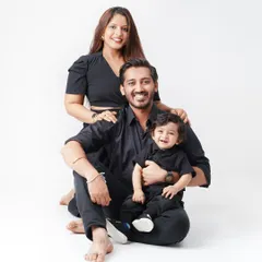 A stylish family portrait with everyone dressed in black, seated together against a white studio background, creating a modern and timeless look.