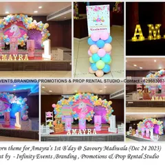 A magical unicorn theme for a first birthday at Savoury Madiwala. This stage setup features a circular backdrop with a pastel rainbow balloon garland, themed cylinder props, and a personalized welcome sign.