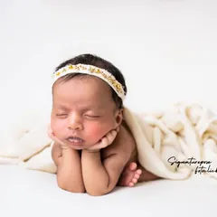 Pure, simple, and perfect. This minimalist portrait on a white backdrop focuses entirely on the newborn's peaceful expression and adorable "chin on hands" pose.