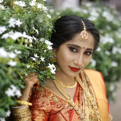 A close up bridal portrait, with the bride framed by white jasmine flowers, highlighting her striking makeup and expression.