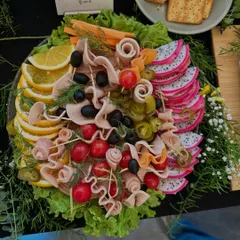 Our charcuterie board is a celebration of textures and flavors, featuring rolled cold cuts, olives, fresh dragon fruit, and citrus slices. It's a vibrant and sophisticated addition to any festive spread.