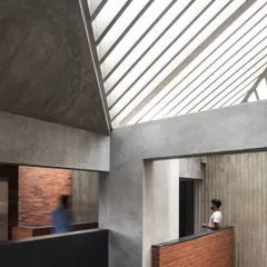 In the Brick House, we created moments of connection between different levels. A view from an upper corridor looks down into a living space, framed by raw concrete and brick, under a skylight that bathes the interior in natural light.