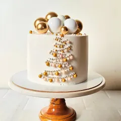 An elegant and minimalist Christmas cake. The simple white design features a Christmas tree made of gold and white sugar pearls, topped with a star.