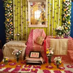For this pooja setup, I created a backdrop with yellow fabric and strings of flowers, framing the Guru Ji's seat. The area is decorated with flower petals on the floor and several vases of fresh flowers, making the space feel sacred and beautiful.