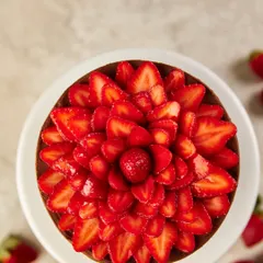 An overhead view of our Chocolate & Strawberry cake, where fresh, thinly sliced Mahabaleshwar strawberries are arranged to look like a blooming flower. This design highlights our commitment to using beautiful, seasonal ingredients as the star of the show.