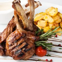 Our grilled lamb chops, perfectly seared and seasoned with rosemary, served with roasted potatoes. A rustic and hearty dish full of Mediterranean flavor.