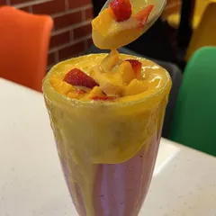 A spoonful of our decadent mango shake, showing its rich texture and fresh fruit toppings. High-quality drinks like this keep customers coming back.