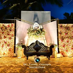 An elegant outdoor Mehendi stage with two stunning floral walls and a modern geometric backdrop. The traditional carved seating contrasts beautifully with the contemporary design elements.
