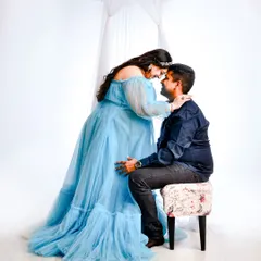An intimate moment between an expecting couple during their maternity session. The mother-to-be's flowing blue dress and the soft white background create a bright and airy feel.