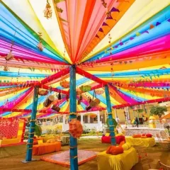 We love bringing energy to pre-wedding functions. This is a Mehendi setup we designed, featuring a vibrant canopy of multi-colored drapes, traditional hanging decor, and comfortable floor seating for a festive and joyful atmosphere.
