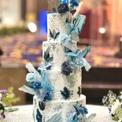 This four-tiered wedding cake is a modern masterpiece. It features a silver leaf finish with abstract blue brushstrokes and is adorned with handmade sugar flowers and rice paper sails.