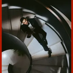 A creative perspective for a groom's portrait. This top-down shot on the spiral staircase creates a dynamic and artistic composition, showcasing his dapper tuxedo.