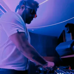 Lost in the rhythm, found in the lights. A candid shot of me mixing in a club with intense purple and blue lighting, completely focused on the next track.