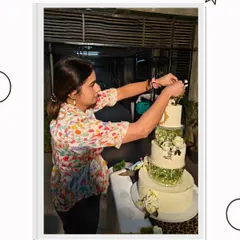 The final touches are always the most important. Here, I am carefully placing the last few sugar flowers on a large wedding cake, ensuring every detail is perfect before it goes to the client.