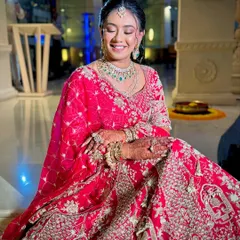 A joyful bride with her hair styled in a floral bun. This timeless updo is a popular choice for its elegance and ability to hold heavy dupattas and jewellery in place.