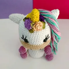 A close-up of the mini unicorn's face, showing her sweet embroidered eyelashes and the tiny flowers on her head.
