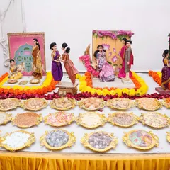 A full view of a baby shower rukhwat table, complete with multiple doll vignettes and an array of traditional sweets and snacks ('rukhwat cha khau') presented in ornate trays.