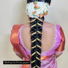 A unique and modern take on a traditional braid. This fishtail braid is accented with a gold ribbon and topped with a fresh flower veni, creating a stylish look for any wedding event.