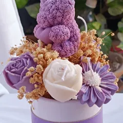 A gift that truly blossoms. This flower bouquet candle features a purple teddy bear candle nestled among an arrangement of purple and white rose candles and dried flowers, all presented in a beautiful box.