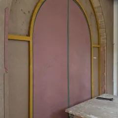 The making of our bespoke entrance door. This image shows the raw MDF and plywood structure, meticulously templated to create the perfect arched form that would later be wrapped in a custom-designed, embellished fabric skin.