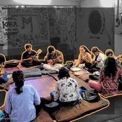 A wide view of our after-school music hub, a creative and inspiring space filled with art and instruments. Here, students gather on the floor for a group ukulele and guitar lesson, fostering a sense of community.