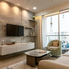 The TV unit in this home is designed to be both a focal point and a functional storage solution, featuring a marble-finish back panel and floating shelves that keep the space feeling open and uncluttered.