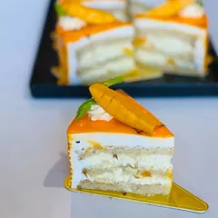 A slice of our light and airy Mango Pastry. It's layered with fresh mango pieces and delicate cream, making it a refreshing and delicious seasonal treat.