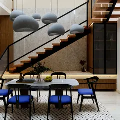 We believe even compact areas can feel spacious and full of light. In this living and dining space from our Yūgen House project, we used a double-height ceiling over the staircase and modern pendant lighting to draw the eye upward, creating a sense of openness. The combination of warm wood, cool marble, and bold blue chairs brings character and elegance to the room.