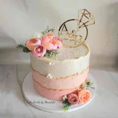 This single-tier engagement cake features a lovely pink ombre effect and is completely free of fondant. It's adorned with fresh flowers and a custom initial topper, making it perfect for a small, personal celebration.