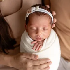 A close-up portrait of a peacefully sleeping newborn, swaddled snugly in white. I focus on capturing the delicate features, like their tiny hands and serene expression, during these quiet moments.