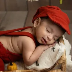 Dressed in a cozy red outfit and cap, this little one sleeps soundly. This portrait captures the warmth and comfort of the newborn phase, a perfect memory for a drizzly Bangalore day.