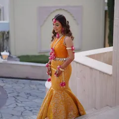 For a sunny Haldi ceremony, I designed this vibrant marigold Banarasi mermaid skirt paired with a hand-embroidered blouse. The fish-cut silhouette is a modern twist on traditional Haldi attire, and the mirror-work tassels add a playful, festive touch.