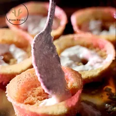 The intricate sweetness of Ghevar, a masterpiece of Indian dessert making. Here, a chef is carefully adding a creamy topping to the delicate, honeycomb-like pastries.