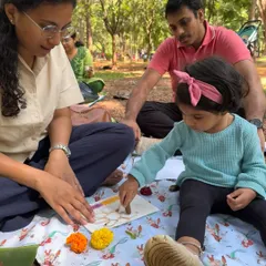 A mother and father sit with their daughter, fully engaged in a creative activity on a beautiful day in the park. It is these simple, shared experiences that I aim to create for families.