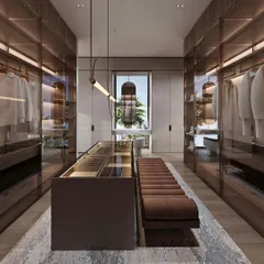 A different view of the bespoke walk-in wardrobe, showing the central island with glass-topped drawers for organizing watches and jewelry. The custom pendant lighting adds a touch of elegance to the functional space.
