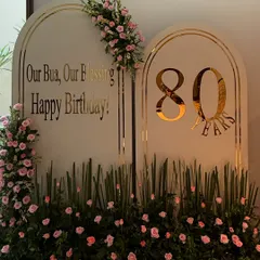 Celebrating a life rich with memories requires decor to match. For this special 80th birthday, we created a personalized backdrop with elegant gold lettering and a garden of fresh pink roses, crafting a space that felt both grand and deeply personal.