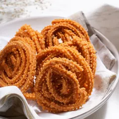 A plate of my fresh Garlic Murukku, a perfect snack for a rainy day alongside a hot cup of filter coffee. Each one is crunchy, flavorful, and made with love.