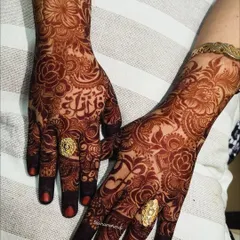 A close-up of the rich henna stain, showcasing the bride's name delicately woven into the floral design on her palm.