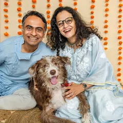A happy family portrait from a Rakshabandhan mini-shoot. The couple smiles warmly with their scruffy, adorable dog, celebrating the festive occasion together.