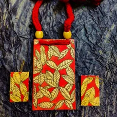 A beautiful shot of the red and yellow leaf-patterned fabric necklace set. The rich colors and detailed painting make this a warm, nature-inspired accessory.