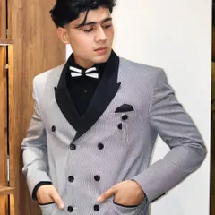 This double-breasted suit in a light grey pinstripe fabric offers a modern take on a classic style. The black peak lapels and matching bow tie create a sharp, contrasting look perfect for any formal event.