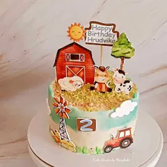 A super cute farm themed cake for a toddler's second birthday. This design features a red barn, a windmill, and adorable farm animals like a cow, sheep, and horse.