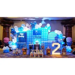 A Boss Baby theme for Jiyan's 2nd birthday. The setup includes a blue sequin backdrop, character cutouts, a light-up number '2', and themed cake stands.