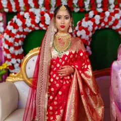 A full-length view of the bride in her beautiful red Banarasi saree. The makeup is designed to complement the richness of the fabric and the grandeur of the occasion.