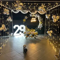 A stylish 29th birthday on a terrace. We created a canopy of fairy lights, a black and silver balloon arch, and added a neon sign and light-up numbers for a stunning nighttime effect.