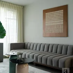 Texture and form come together in this contemporary living room. The vertically channeled sofa is a bespoke creation, designed to offer visual interest and exceptional comfort. The minimalist side tables and curated art piece complete this look of understated luxury.